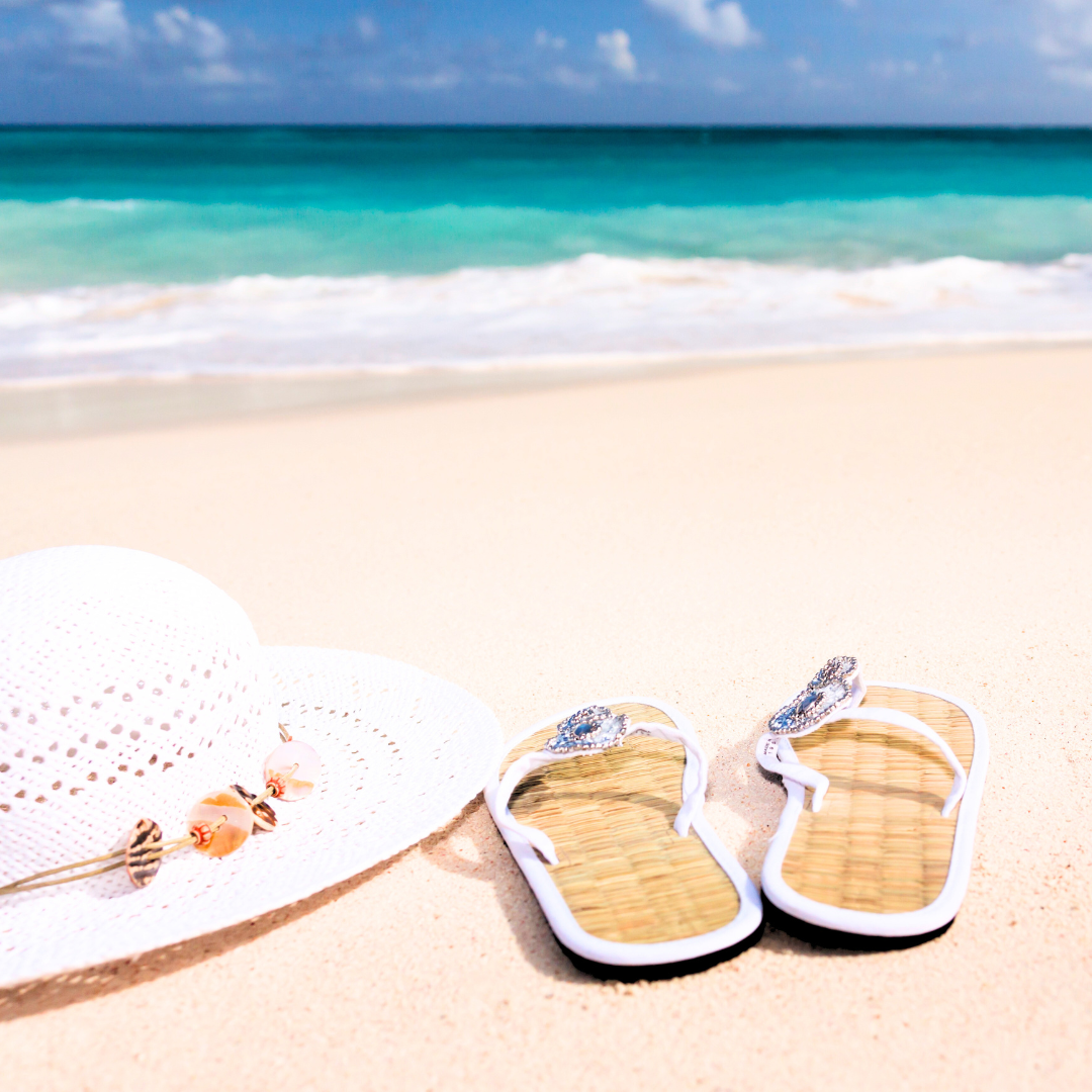 flip flops and a sunhat sitting on the sand at the beach